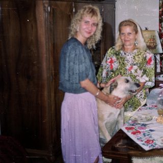Woman and elderly woman with dog in a decorated room.
