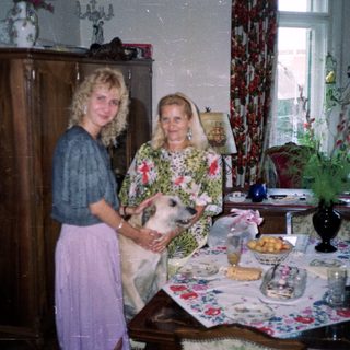 Woman and elderly woman with dog in a decorated room.