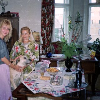 Woman and elderly woman with dog in a decorated room.