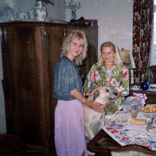 Woman and elderly woman with dog in a decorated room.