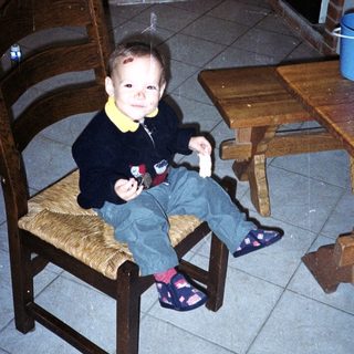 Child sits on a chair in a kitchen.