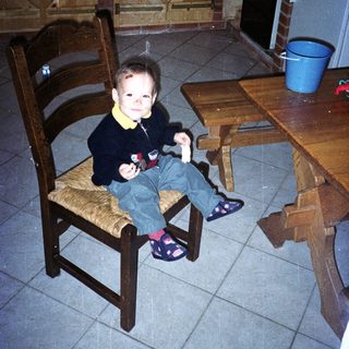Child sits on a chair in a kitchen.