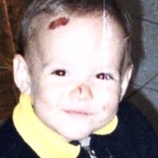 Child sits on a chair in a kitchen.
