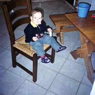Child sits on a chair in a kitchen.