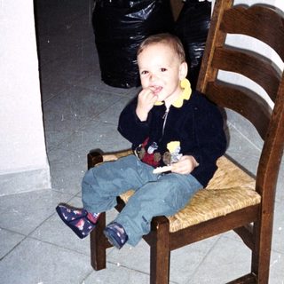 Young child sits on a chair in a tiled room.