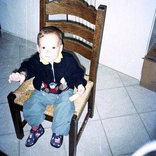 A young child sits on a chair in a room.