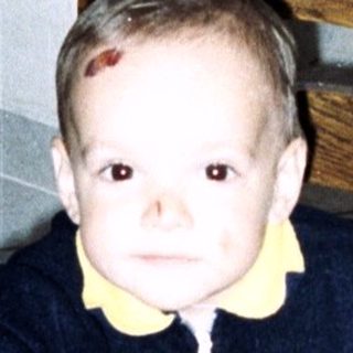 A young child sits on a chair in a room.