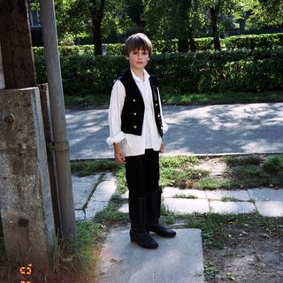 Boy stands outdoors next to a utility pole.