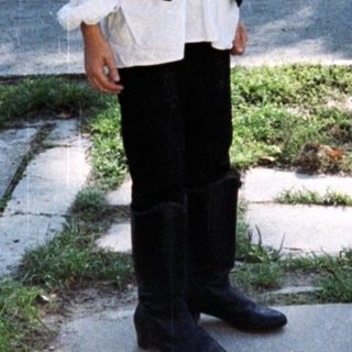 Boy stands outdoors next to a utility pole.