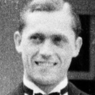 Man in a suit stands outside a building.