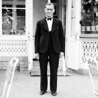 Man in a suit stands outside a building.