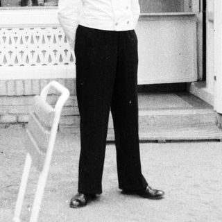 Man in formal wear stands outside a building.