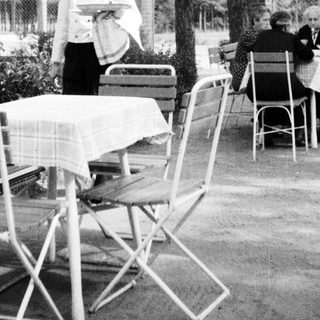 Black and white photo of a waiter at an outdoor cafe.
