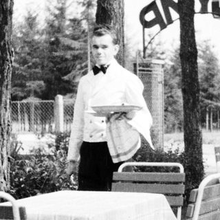 Black and white photo of a waiter at an outdoor cafe.