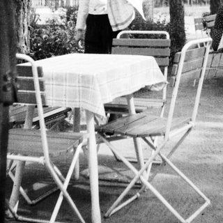 Black and white photo of a waiter at an outdoor cafe.