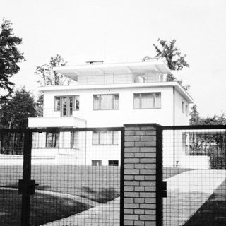 Black and white photo of a modern house and gate.