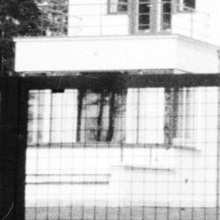 Black and white photo of a modern house and gate.