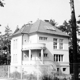 Black and white photo of a vintage house with a balcony.