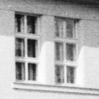 Black and white photo of a vintage house with a balcony.