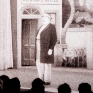 Stage set depicting a building with a person standing before it.