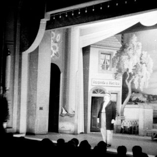 Stage set depicting a building with a performer on stage.