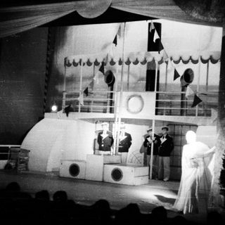 Stage set depicting a ship, performers in costume.
