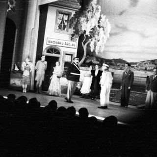 Stage performance with actors and a visible backdrop.