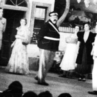 Stage performance with actors and a visible backdrop.