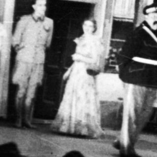 Stage performance with actors and a visible backdrop.