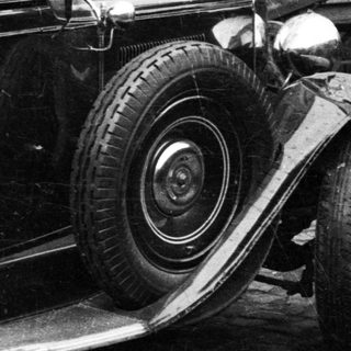 Vintage car parked next to a building and cart.
