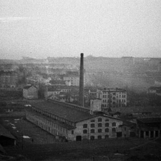 Industrial complex with smoke stack under a hazy sky.