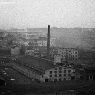 Industrial complex with smoke stack under a hazy sky.