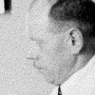 Man seated at a desk, appearing to be writing.