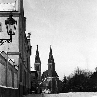 Snow-covered street leads to a church with twin towers.