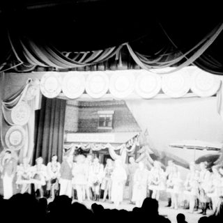 Black and white photo of a stage performance with a group.