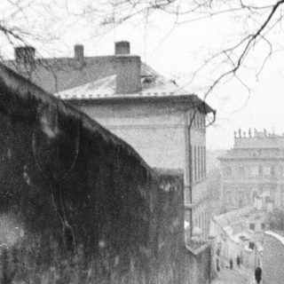 People walk along a path between stone walls.