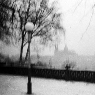 Overcast scene with a lamppost, fence, and distant building.