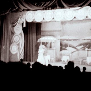 Stage performance with backdrop and audience silhouettes visible.