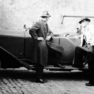 Two men standing near a vintage car.