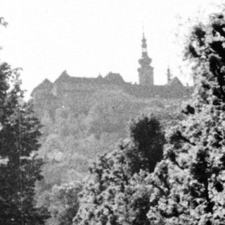 A path leads towards a city with a church spire.