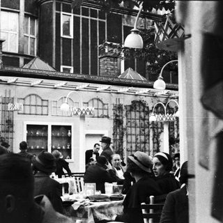 People dining outdoors at a restaurant, vintage style.
