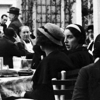 People dining outdoors at a restaurant, vintage style.