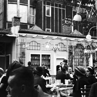 People dining outdoors at a restaurant, vintage style.