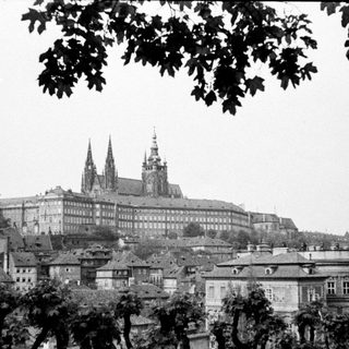 Black and white view of Prague Castle and city rooftops.