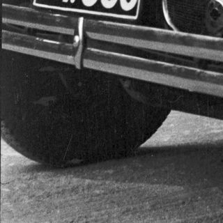 Black and white photo of a vintage car's front.