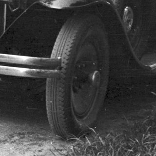 Vintage car and man standing on a dirt road.