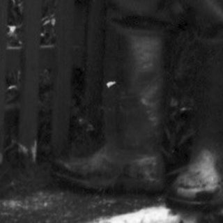 Man stands near a house with a picket fence.
