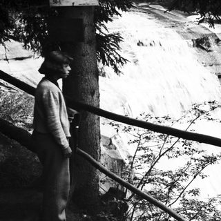 Person observes a waterfall with warning sign nearby.
