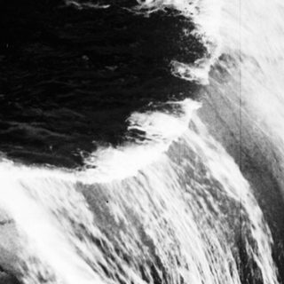 A waterfall cascades down rocky terrain in black and white.