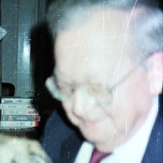 Older man pets a dog in a home setting.